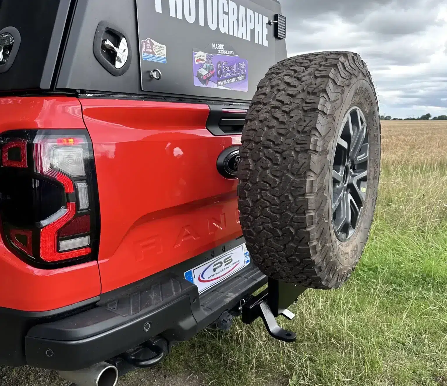 Roue de secours sur 4x4 rouge en campagne.