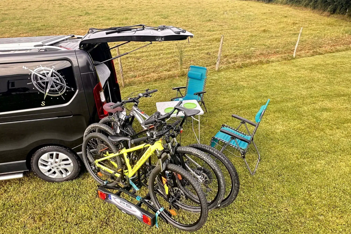 Camping-car avec vélos et chaises en pleine nature.
