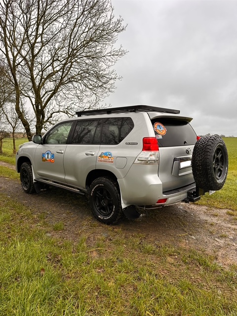 SUV gris avec autocollants stationné en campagne.