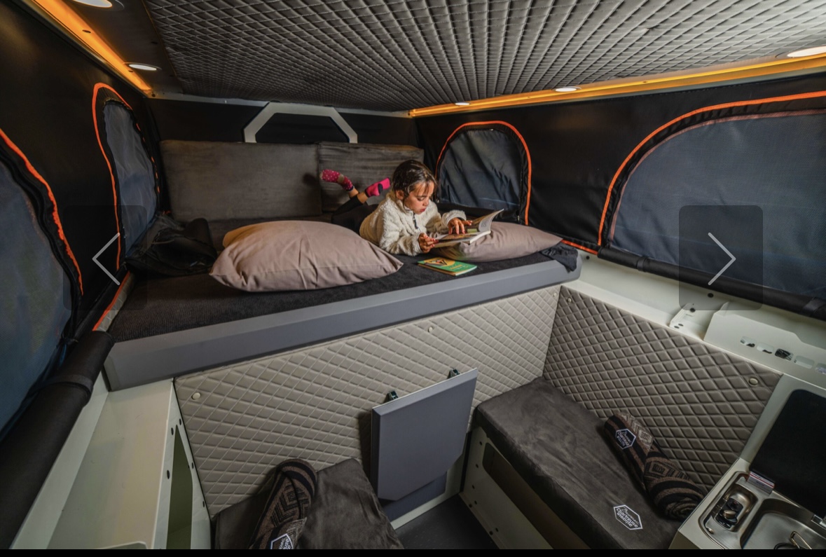 Screenshot Enfant lisant dans une couchette de van aménagé.