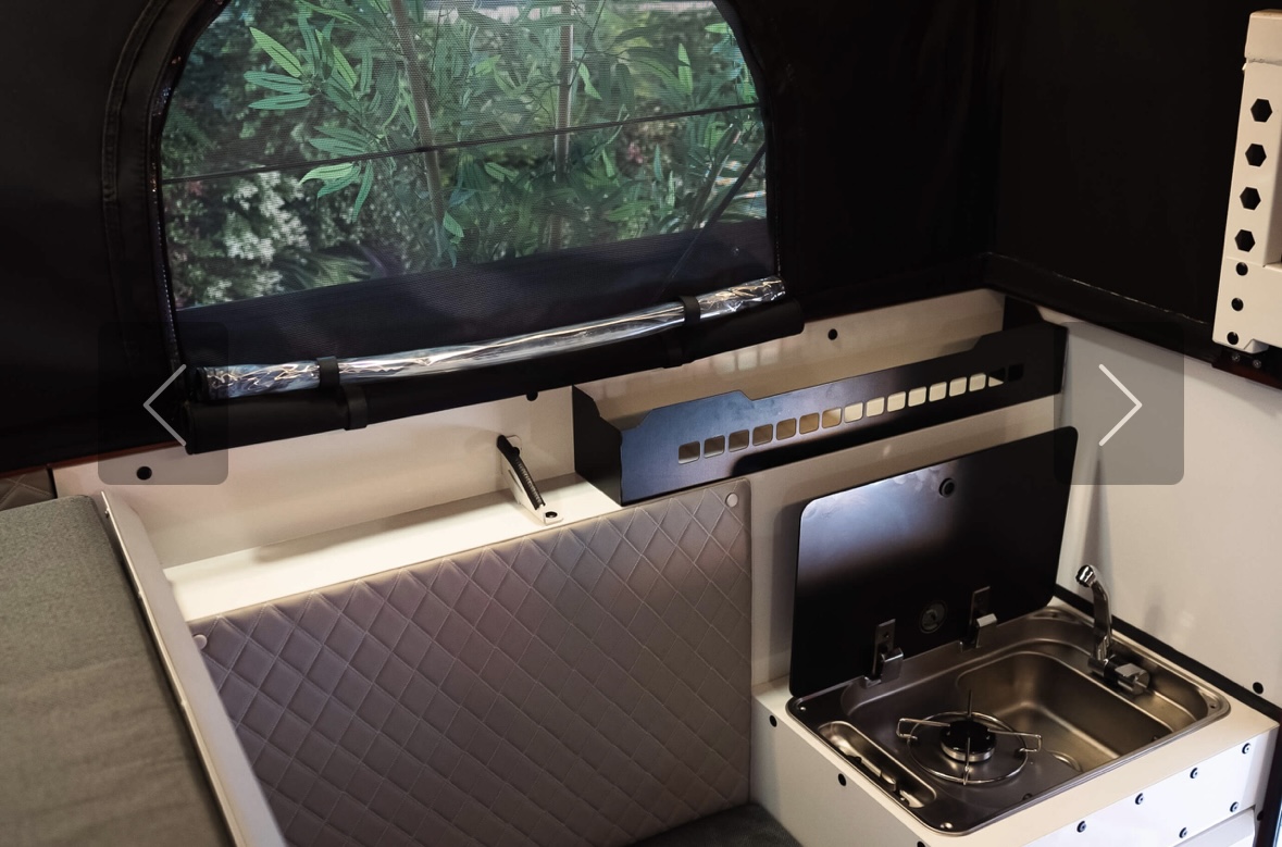 Screenshot Intérieur de van aménagé avec cuisine compacte.