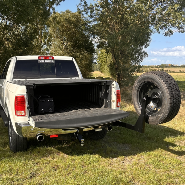 Pick-up blanc avec hayon ouvert et roue de secours.